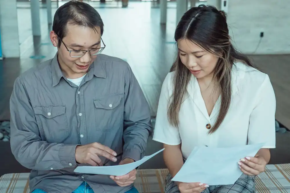 Two colleagues reviewing project documents together in an office